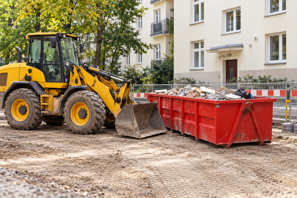 Żółta ładowarka przy czerwonym kontenerze